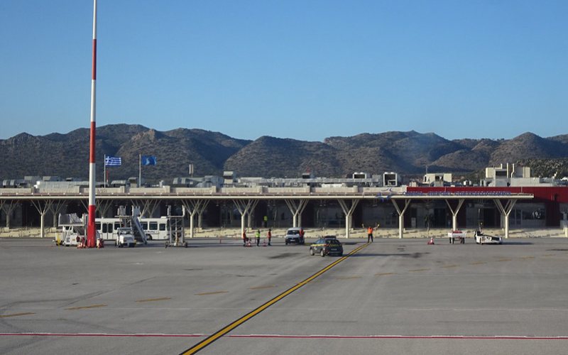 Chania airport image with cars and bus standing there.