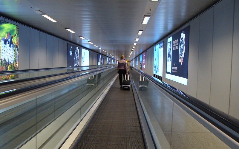 Woman with a trolly bag at Geneva International Airport.