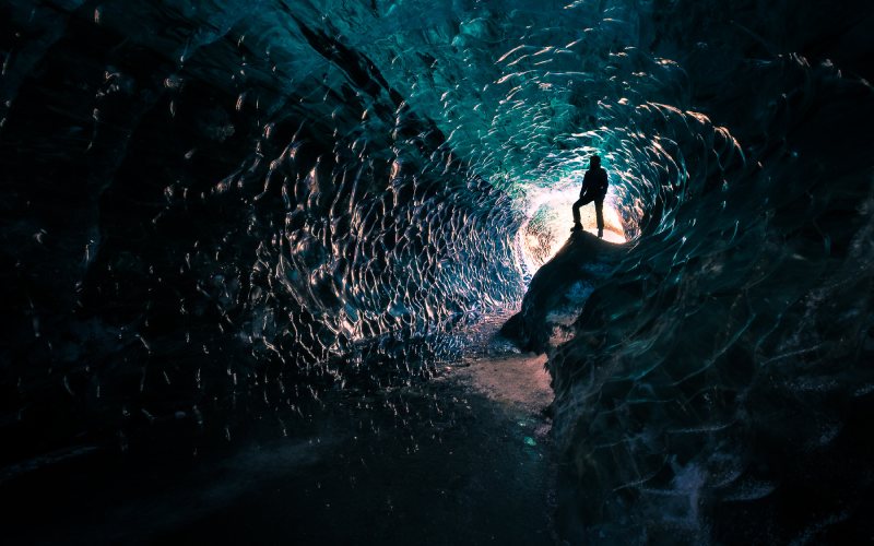 A man standing inside ice caves in Iceland.