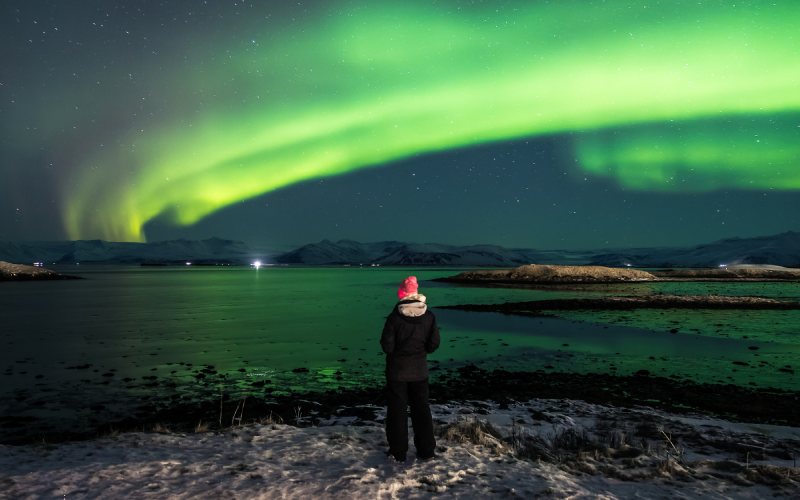 A man wearing black jacket enjoying the Northern Lights in Iceland.