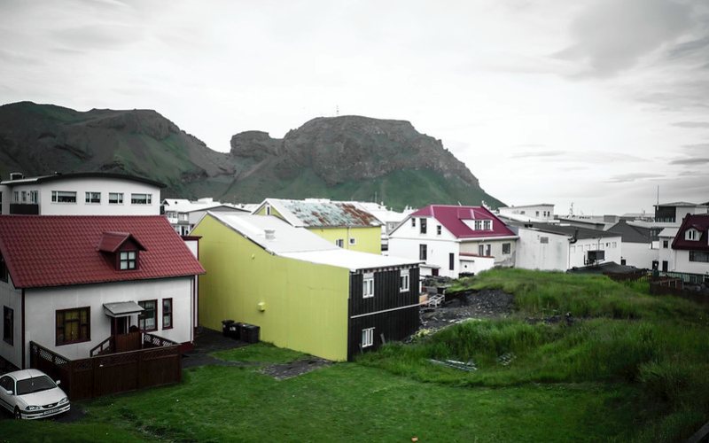 So many houses near with huge mountains visible at the back in Vestmannaeyjar.