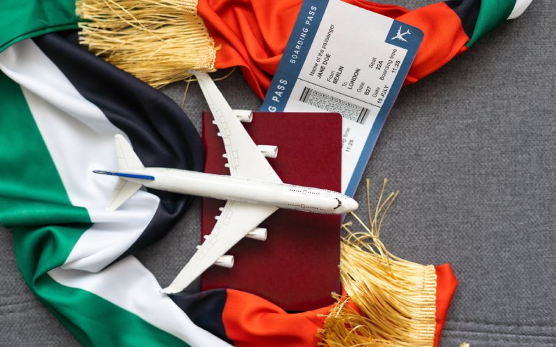 Passport and a united arab flag on a grey backgroung with a boarding pass .