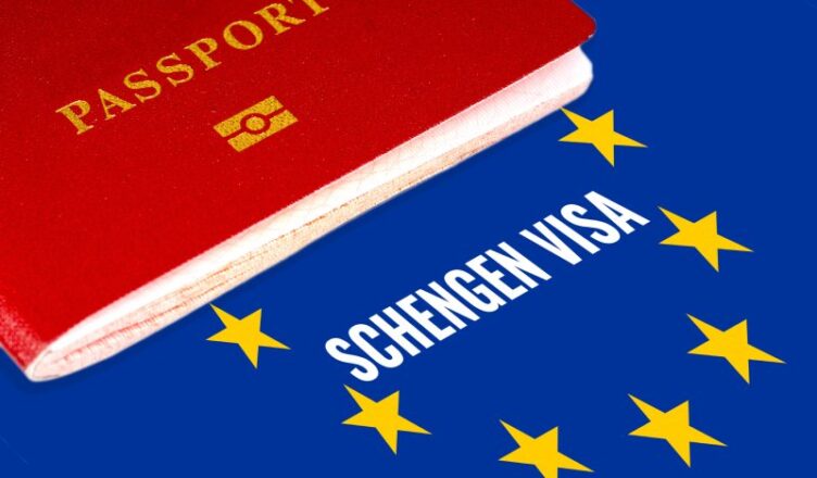 Schengen visa written on Europe flag with a passport laid over it.