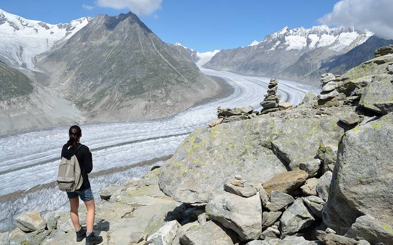 A Girl with backpack Hiking along the Aletsch Glacier, Switzerland