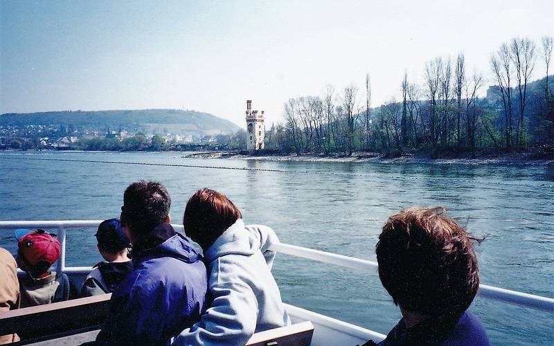 People enjoying scenic views at Rhine river cruise in Germany.