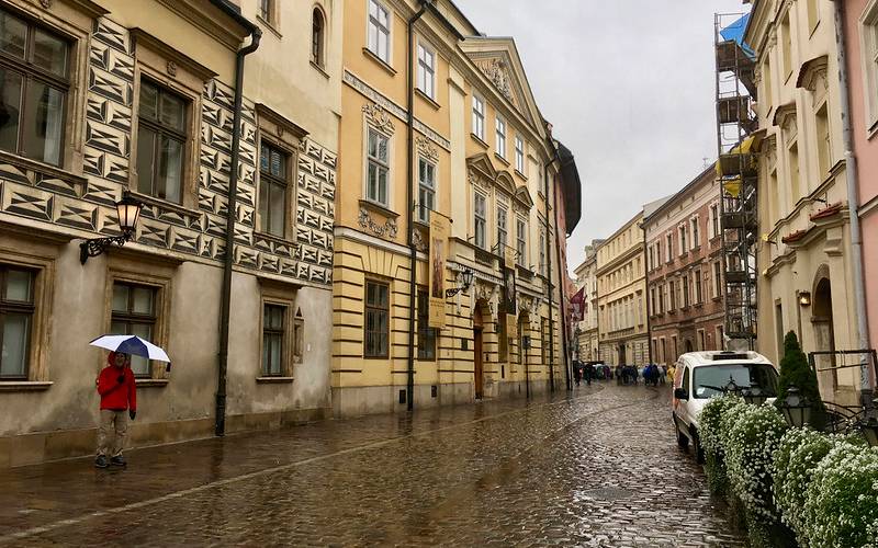 A man standing with an umbrella at the streets of Krakow in Poland.