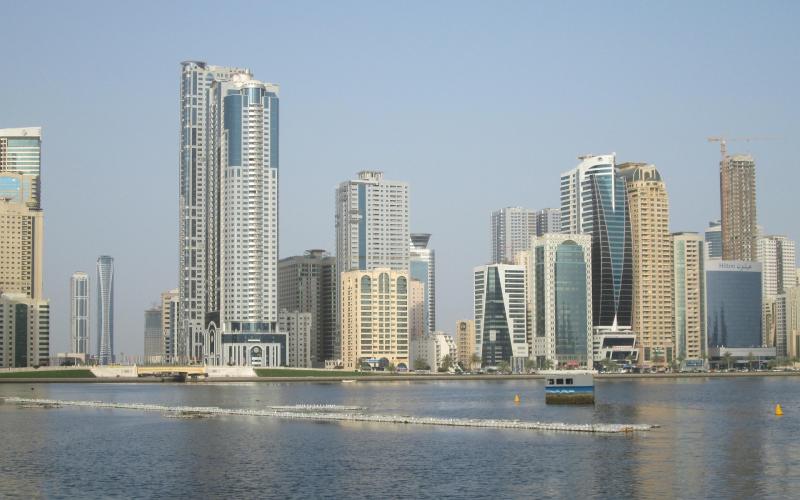 Tall buildings in Sharjah, UAE overlooking a waterway with a boat